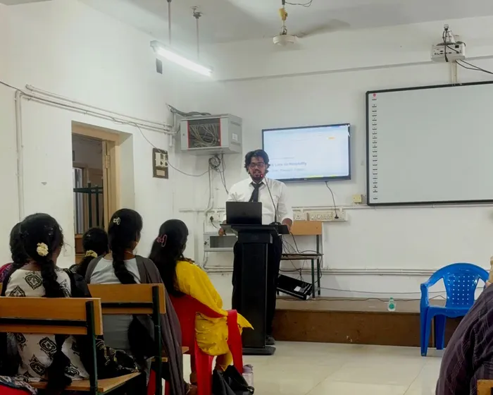 Pramodh Kuppan speaking at the podium to hotel management students at Alagappa University